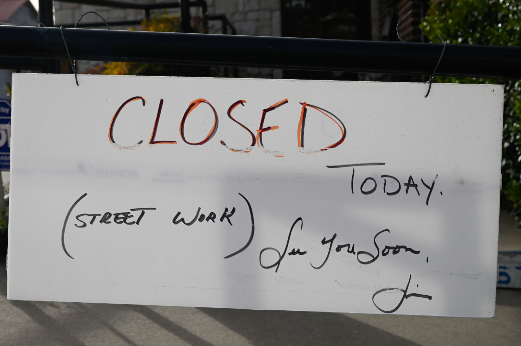 Closed sign in front of Cadillac